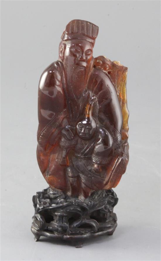 A Chinese amber group of a sage and a boy, Qing dynasty, attached to a wood stand, losses